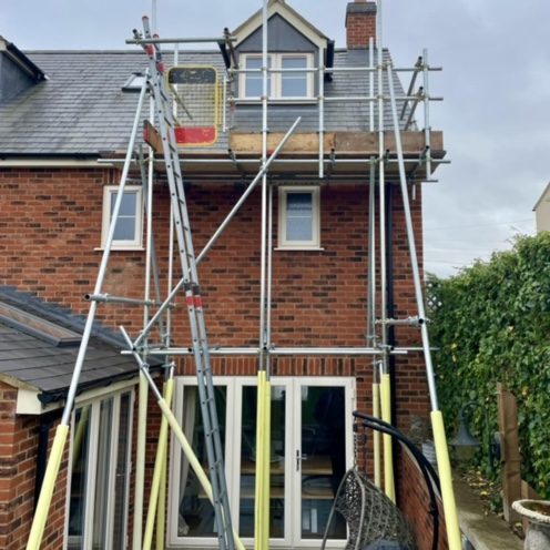 Scaffolding set up outside a brick house for repair work on the roof.