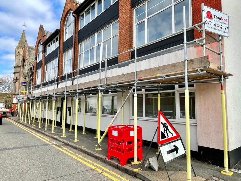Scaffolding under construction on a building with traffic signs nearby.